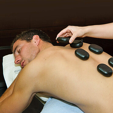 Man ontvangt massage met warme stenen