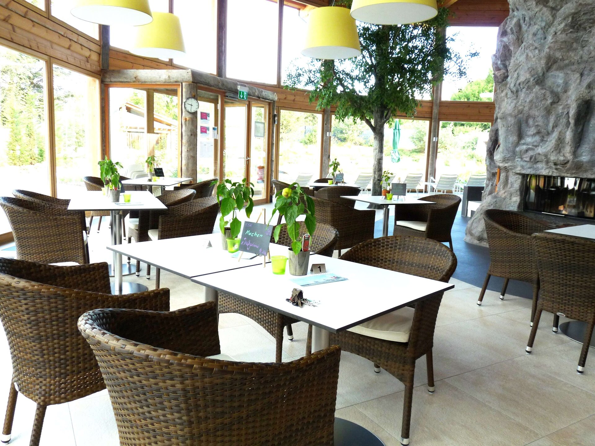 Finlounge met tafels en stoelen en groot glazen raam met uitzicht op de tuin