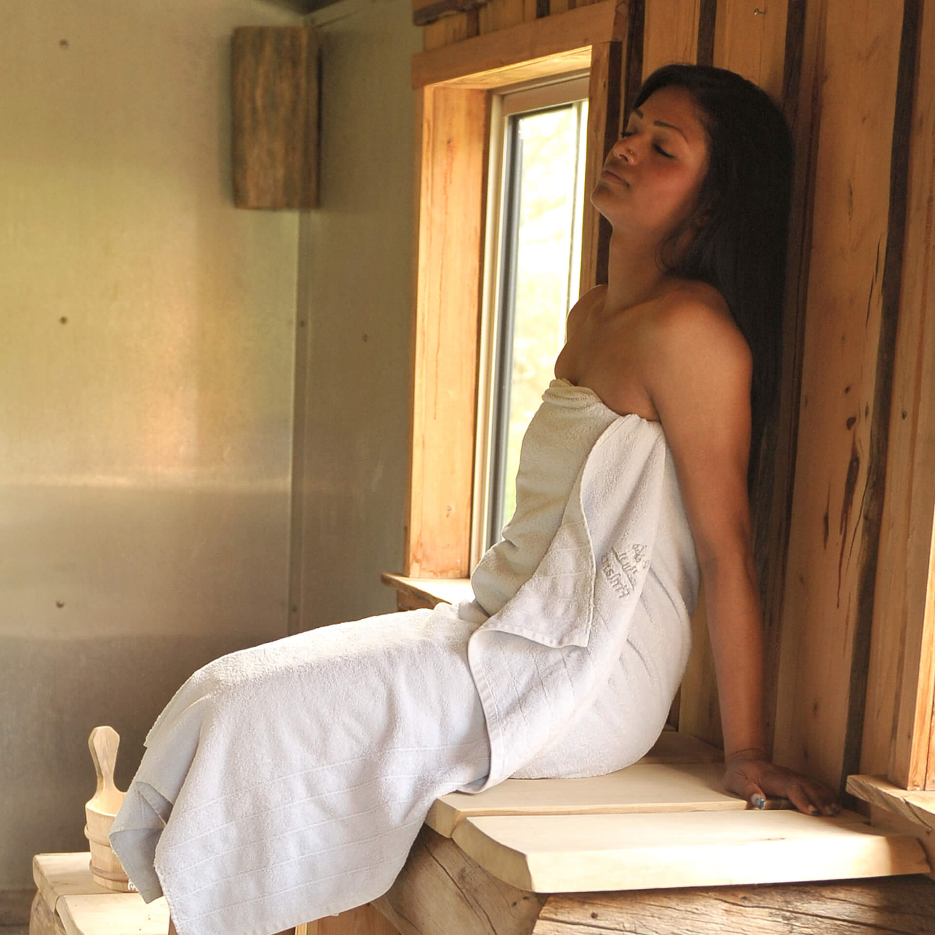 Frau geniest heißen Sauna-Aufguss
